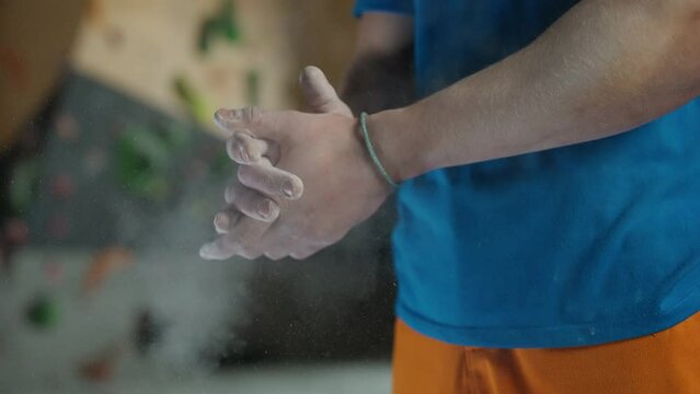 Climber puts magnesia on his hands before training on a climbing wall.