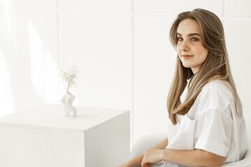 Fototapeta na wymiar Portrait of a pretty cute young girl. Beautiful positive girl in a white cotton shirt. Copy space