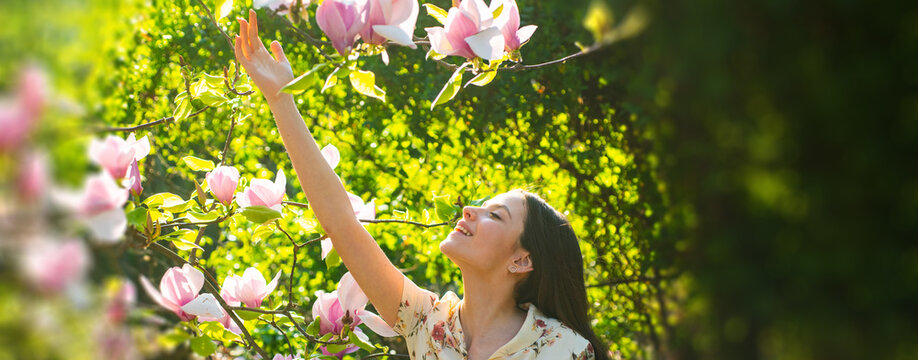 Spring woman face for banner. Young girl on Spring flowers background. Magnolia. Beautiful young woman with blossom branch, young woman in spring blossom garden.
