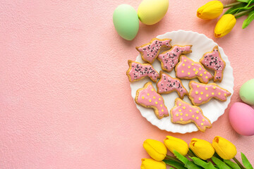 Homemade easter cookies in the shape of bunnies with icing and sprinkles on pink background, space for text
