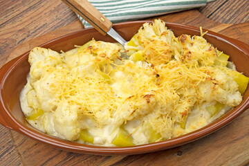 Cauliflower and potato gratin in a dish on a wooden board