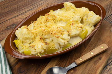 Cauliflower and potato gratin in a dish on a wooden board