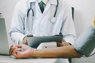 doctor measures the blood pressure of an elderly male patient.