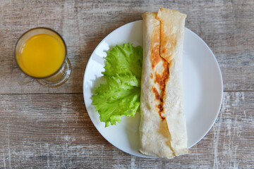 Shawarma with meat, cutaway, with sauce, tomatoes, cheese, herbs and garlic, wood background