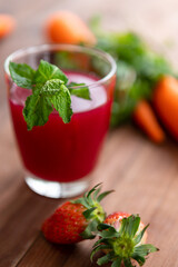 Close up studio shot of two glasses of freshly blended squeezed strawberry and carrot healthy diet vegan drink fresh fruit vegetable beverage placed on wooden table for advertisement with copy space