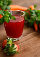 Close up studio shot of two glasses of freshly blended squeezed strawberry and carrot healthy diet vegan drink fresh fruit vegetable beverage placed on wooden table for advertisement with copy space