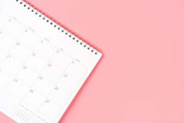 White calendar on pink background close up with copy space.