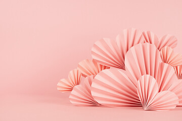 Valentines day scene in asian style - pink paper hearts of folded fans on pastel pink color, border, copy space, closeup. Romantic stage mockup for presentation cosmetic product, goods, card, poster.