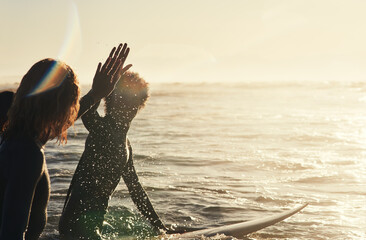 Keeping the vibe going. Shot of a group of young surfers surfing together in the ocean.