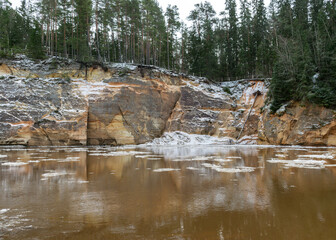 the river in early spring, sandstone outcrop, ice cubes in the water, river bank from the opposite bank, Erglu cliffs, river Gauja, Cesis, Latvia