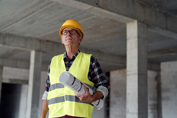 Senior caucasian man holding plans on the construction site