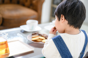 おやつをコッソリ食べようとする子ども笑 顔無し 後ろ姿