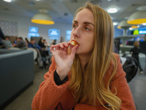 Woman eating chicken by hands on food court in mall