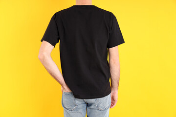 Obraz premium Man in blank black t-shirt on yellow background