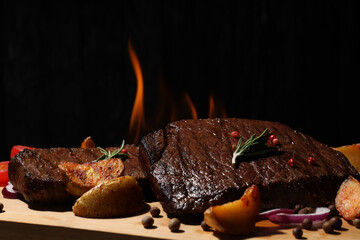 Concept of tasty food with beef steaks on dark background