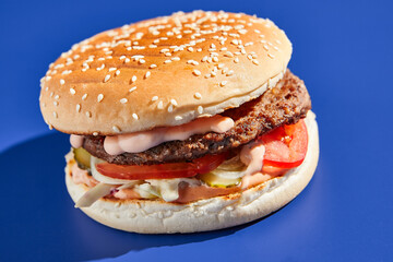 Beef burger blue background with hard shadow. American junk food minimal style. Hamburger trendy style.  Simple burger colour background.