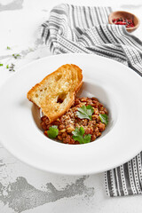Georgian lobio in white plate with bread. Traditional georgian dish from red bean in sauce and spices.  Vegetarian appetizer from georgian cuisine. Caucasus lobio in restaurant menu. Vegan food.
