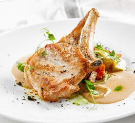 Roasted pork steak with vegetables garnish and sauce. Bone-in ribeye pork chops. Main course of...