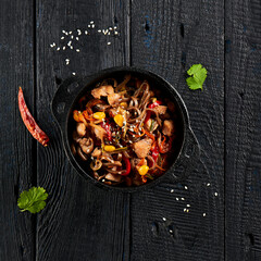 Yakisoba noodle with chicken and vegetables on wooden background. Japanese stir fry noodles in wok...