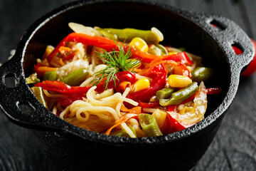 Vegetarian stir fried noodles on dark background. Asian vegan pasta on wok. Veggie wok on black wooden table. Spaghetti with vegetables on chinese style. Thai food menu..
