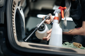 Woman cleaning car salon with polishing spray in car detailing service