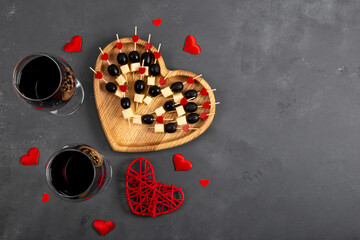 Two glasses of red wine and cheese with olives on skewers. Light snack and wine for a romantic date...