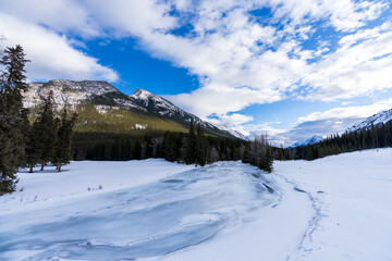 Frozen Bow River in winter, snowcapped Canadian Rockies in the background. Beautiful scenery in Banff National Park, Alberta, Canada.