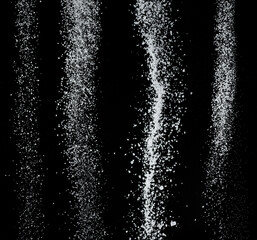 White refined sugar crystals falling down at black background.