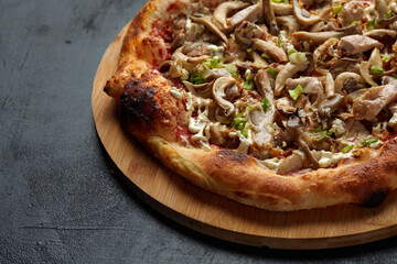 Delicious homemade pizza with mozzarella, mushrooms, beef and chicken. Dark background, selective focus.