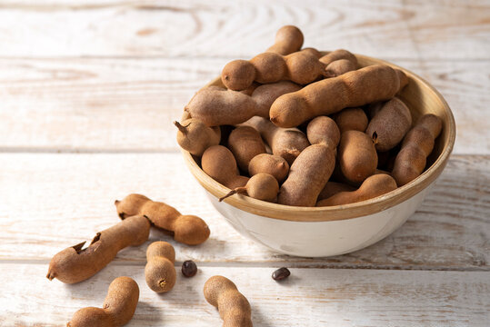 Fresh Tamarind fruits (Tamarindus indica, Indian date) Sweet ripe tamarinds on white wood rustic background. close-up	
