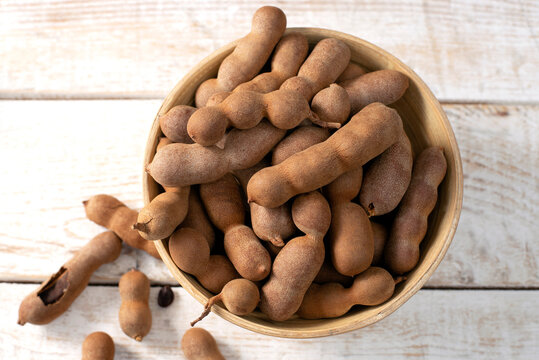 Fresh Tamarind fruits (Tamarindus indica, Indian date) Sweet ripe tamarinds on white wood background. top view