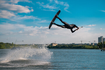 Professional wakeboarder performing jump over water while holding on tow rope