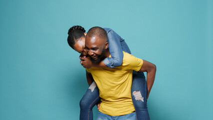 People having fun together with piggy back ride in front of camera. Man and woman enjoying playful...