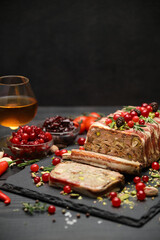 Traditional French terrine covered with bacon on dark wooden background with Christmas decorations