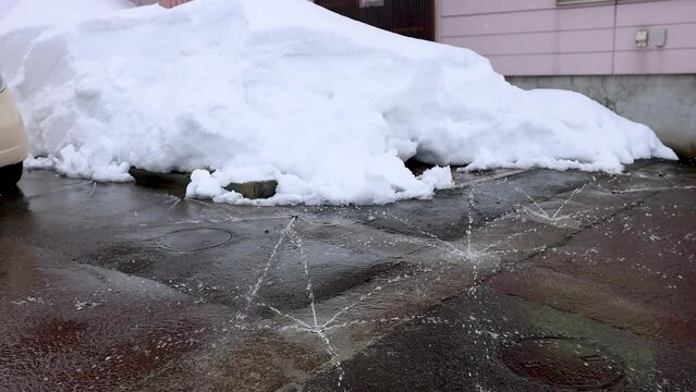 雪が積もった駐車場と水が噴き出す消雪設備