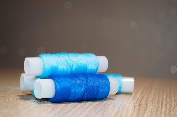 Fototapeta na wymiar Bright blue spools of thread on table on blurry background