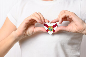 Flag of the State of Florida in the shape of a heart in the hands of a girl. Love Florida. The concept of patriotism