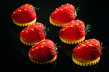Red chocolate candies on a black isolated background in the form of a heart