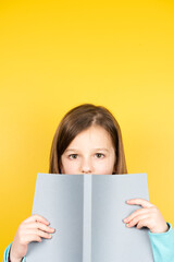 Child holding a book and looking to camera. Yellow copy space.