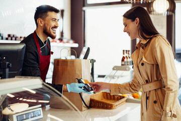 Young woman paying credit card for purchases in grocery store.