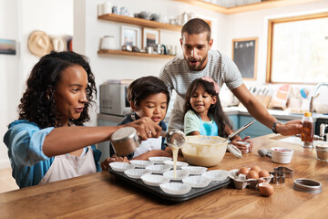 This is where the magic starts. Cropped shot of a young couple baking at home with their two...
