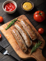 Catfish kupaty on a wooden cutting board with tomatoes, sauce, rosemary.