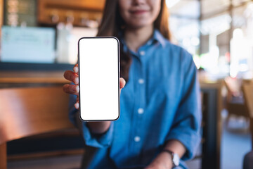 Mockup image of a young asian woman holding and showing a mobile phone with blank white screen