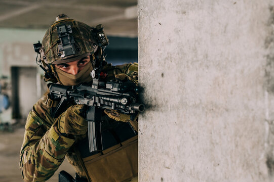 Special forces operator wearing Multicam uniform and his assault rifle HK 416 while practicing CQB combat training in the abandoned building. Coyote brown and mc gear in the urban environment.