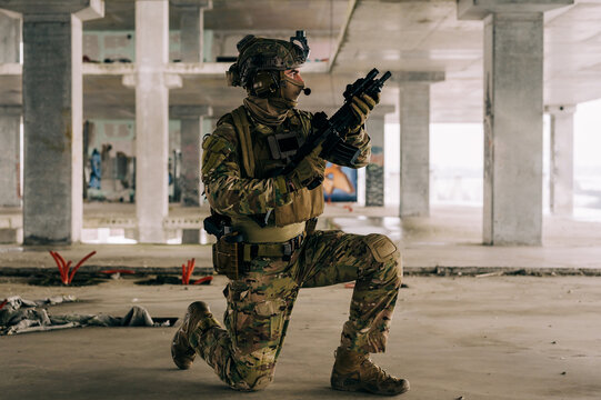 Special forces operator wearing Multicam uniform and his assault rifle HK 416 while practicing CQB combat training in the abandoned building. Coyote brown and mc gear in the urban environment.