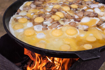 Large frying pan with fried eggs and bacon. Kitchen on a hike.