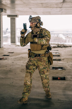 Special forces operator wearing Multicam uniform and his handgun xdm 9mm while practicing CQB combat training in the abandoned building. Coyote brown and mc gear with gun in the urban environment.