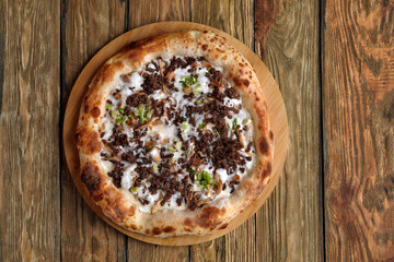Delicious homemade pizza with mozzarella, mushrooms, beef and chicken. Wooden background, selective focus.