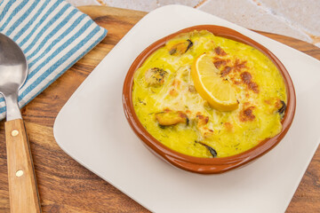 scallop and mussel gratin on a white plate on a table