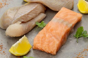 Fototapeta na wymiar salmon steak and raw coalfish fillet on a gray background with lemons